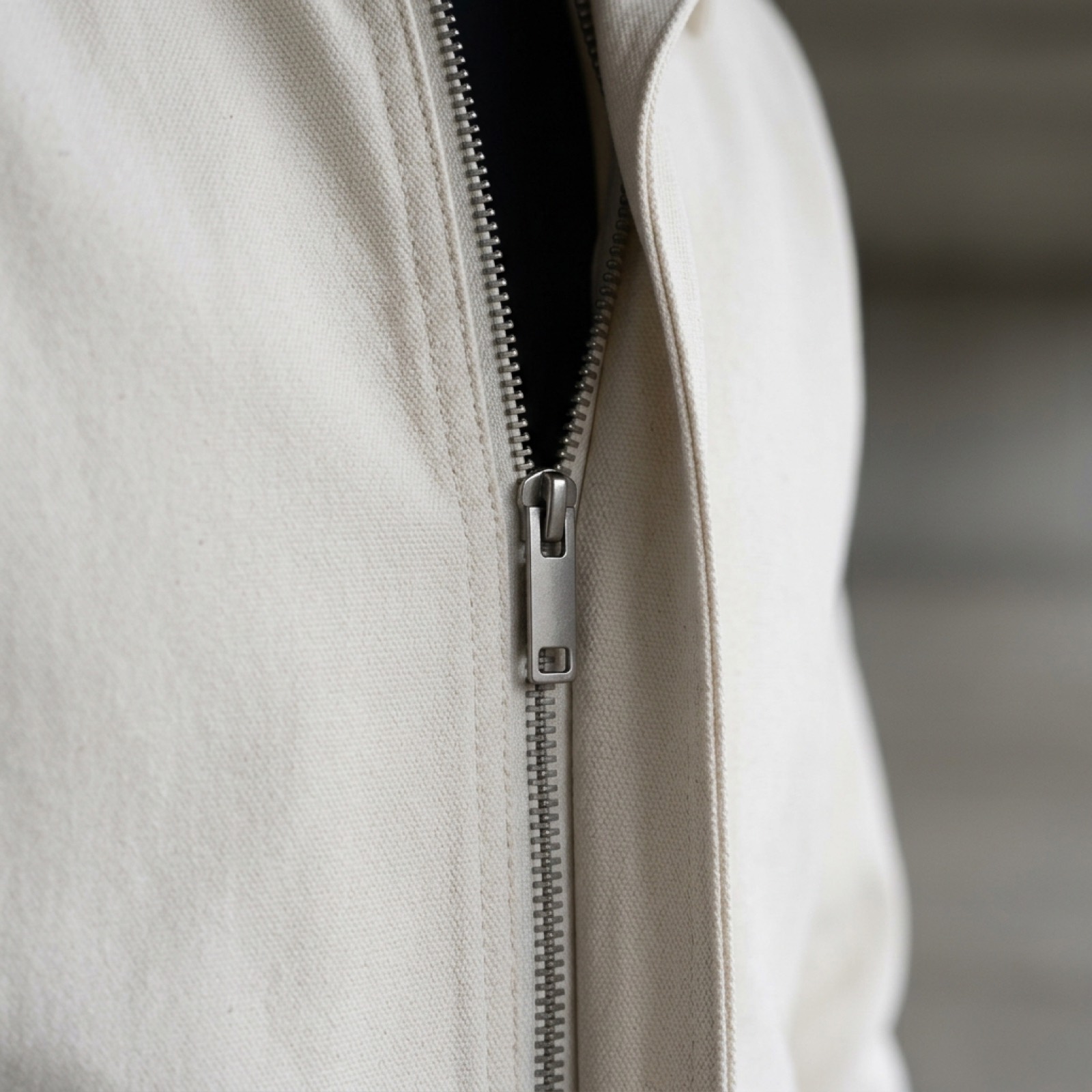 Close detail of the jacket's steel zip and the stitching beside it.